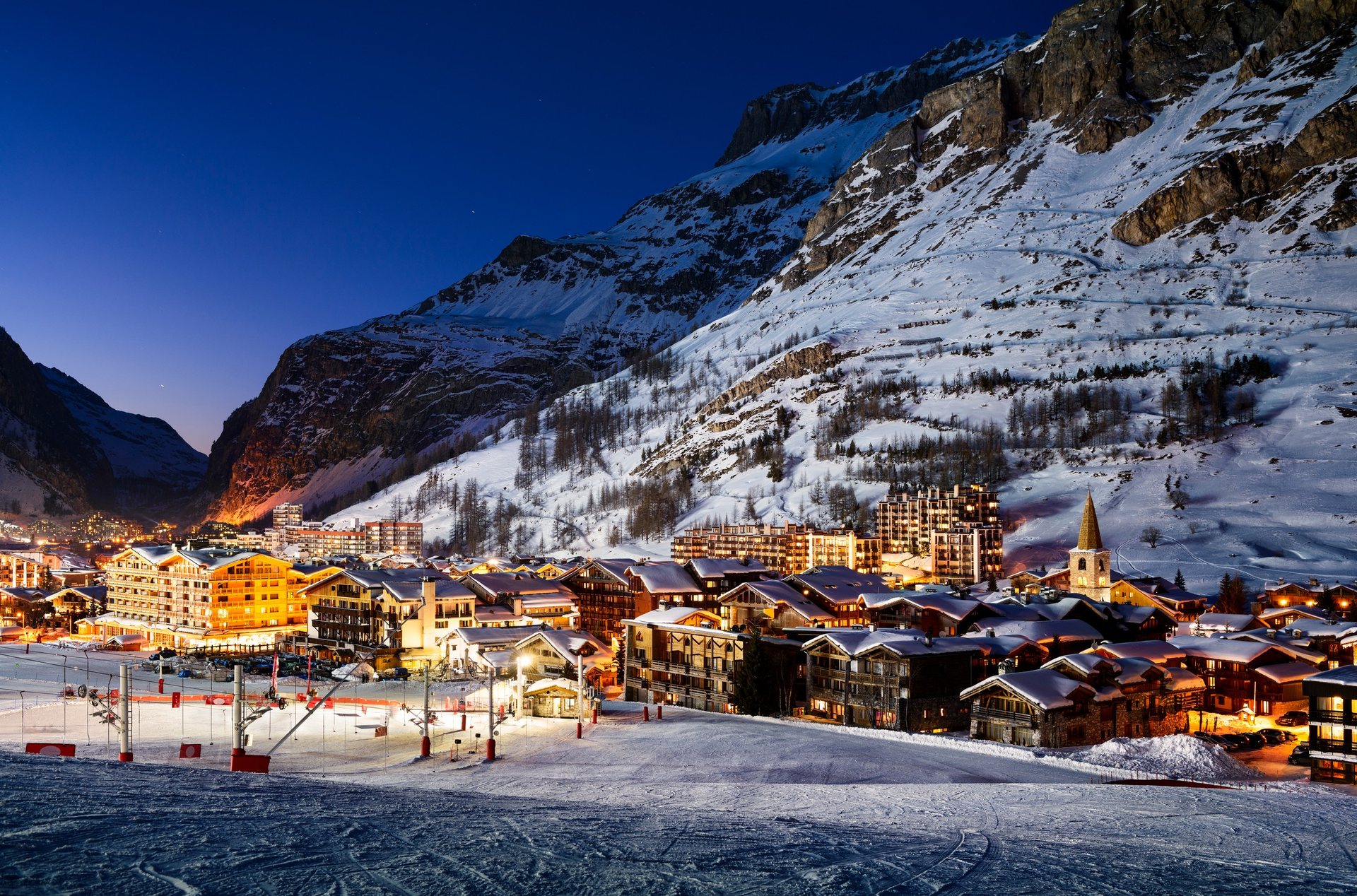 Snow-covered village and illuminated chalets at night in Val d’Isère