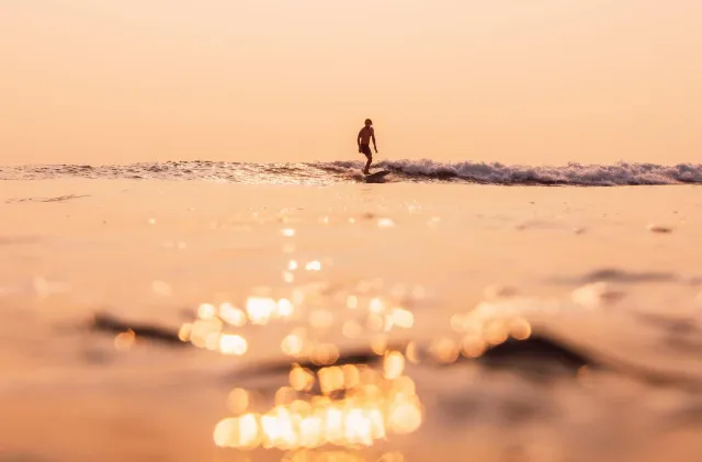 A surfer riding a sunrise wave.