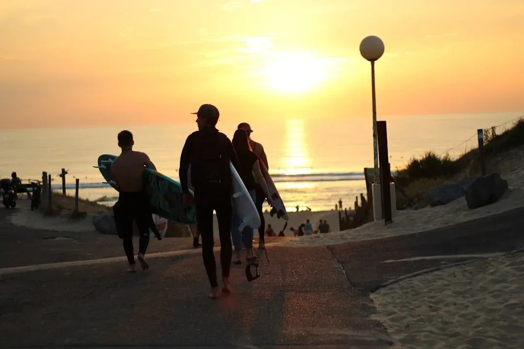 Surfers walking to Le Penon beach at sunset in Seignosse, France