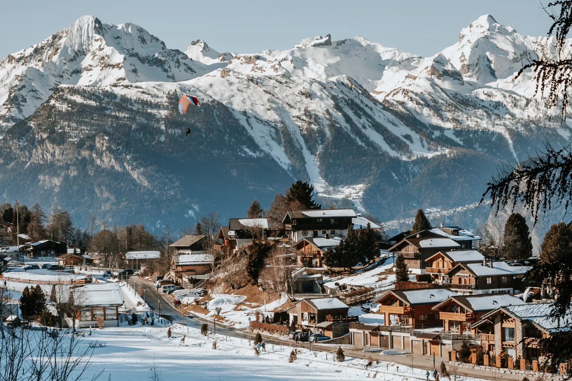 Paraglider above the winter village of Nendaz and snow-covered Valais peaks