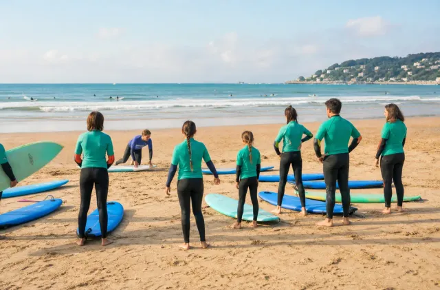 Family-friendly Hendaye surf school group preparing softboards on the sand before a lesson.