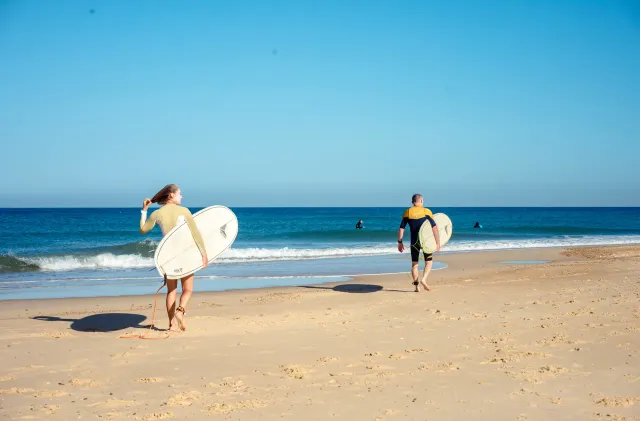 Surfers walking toward the ocean for a beginner lesson near Le Penon beach in Seignosse.